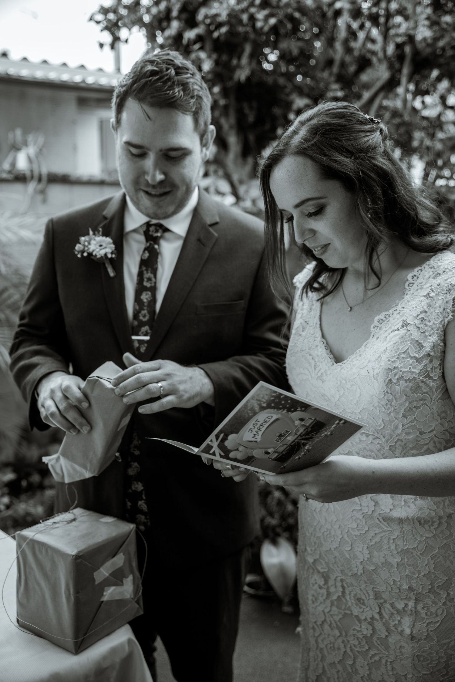 A couple looking down at gifts and papers during an outdoor celebration.