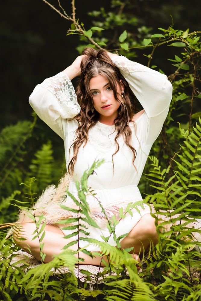 Ethereal forest photography with white dress amid natural ferns.