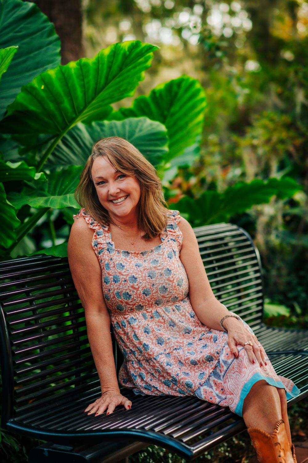 A floral dress and brown boots create a charming look against tropical garden scenery.