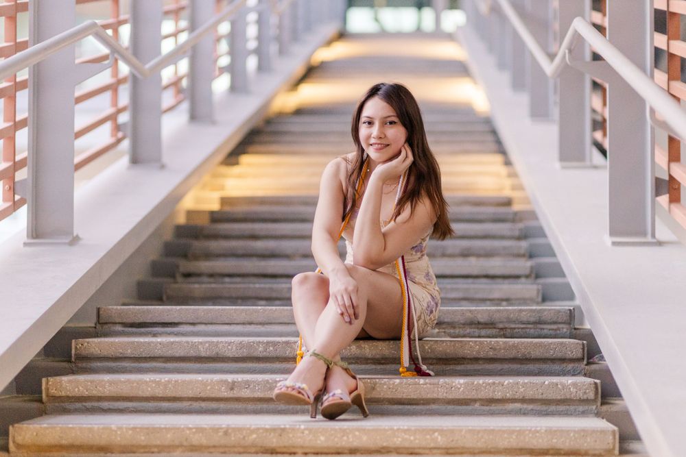 Elegant pose on illuminated staircase wearing beige outfit and heels.