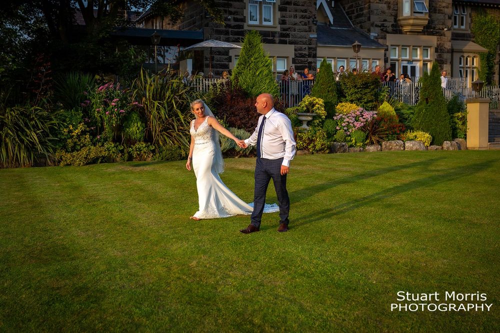 Bride and groom walk hand in hand in the grounds at west tower about to start their first dance.