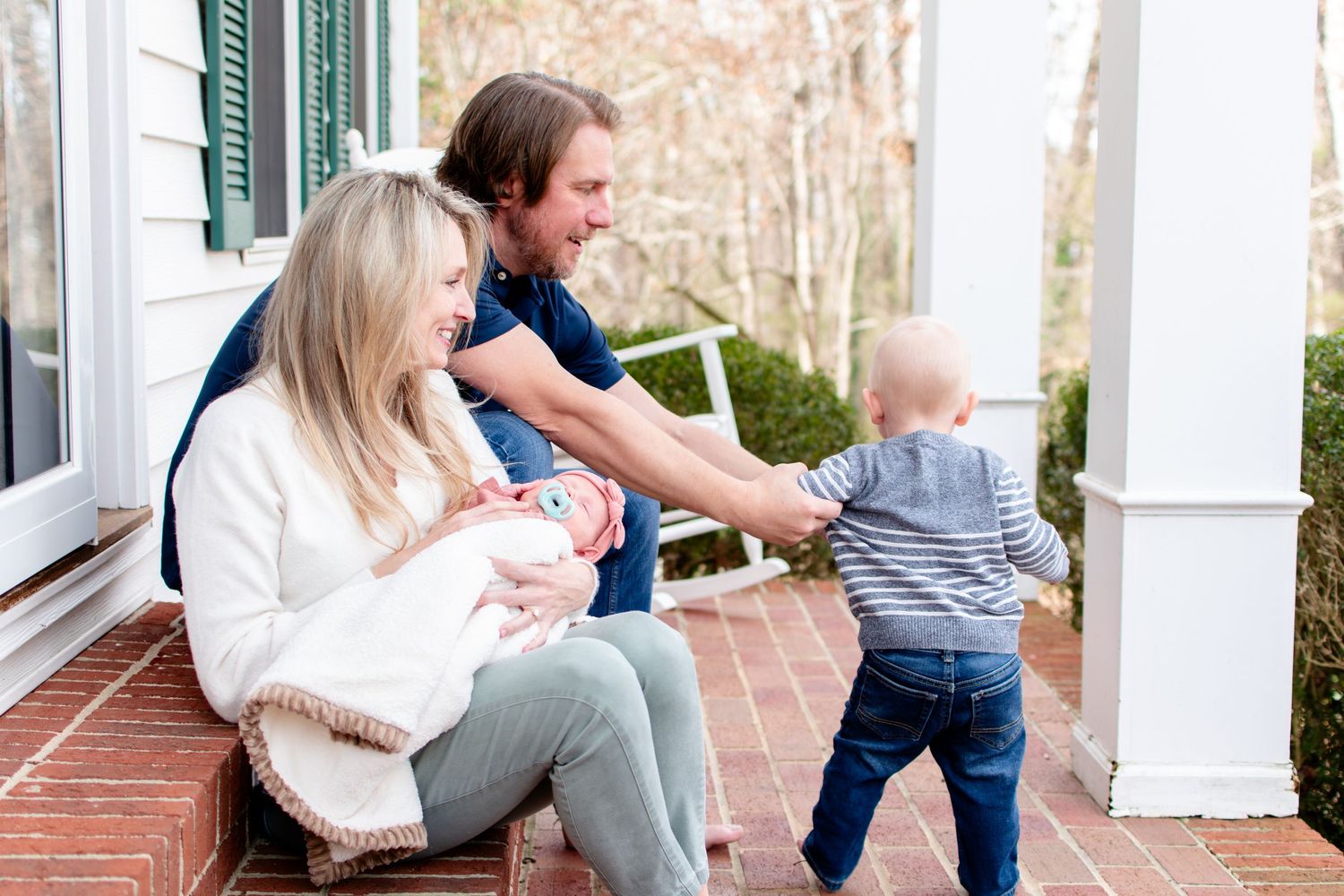 Family spending time together on brick porch with baby and toddler.