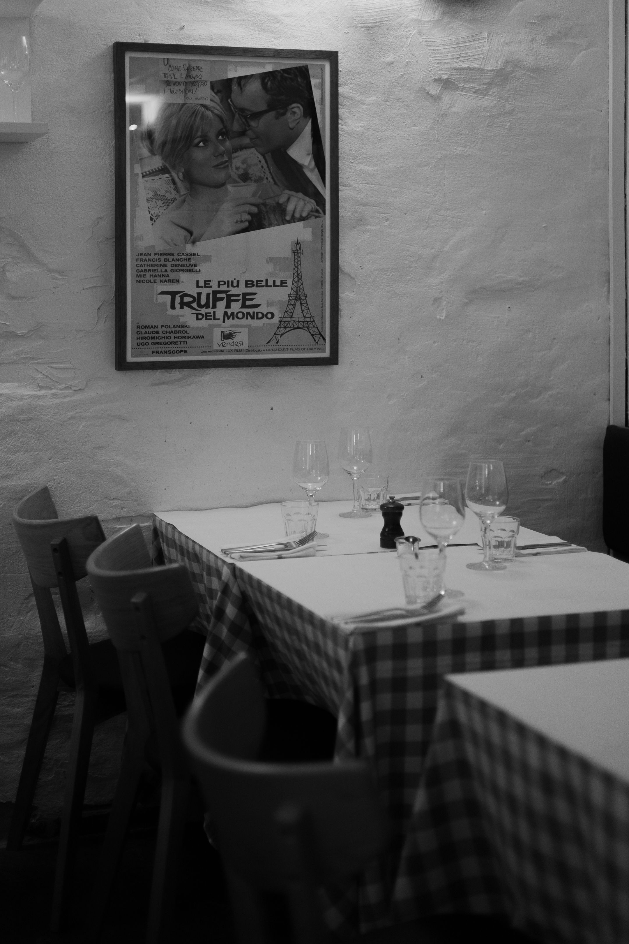 Black and white interior of restaurant with checkered tablecloth and vintage movie poster.