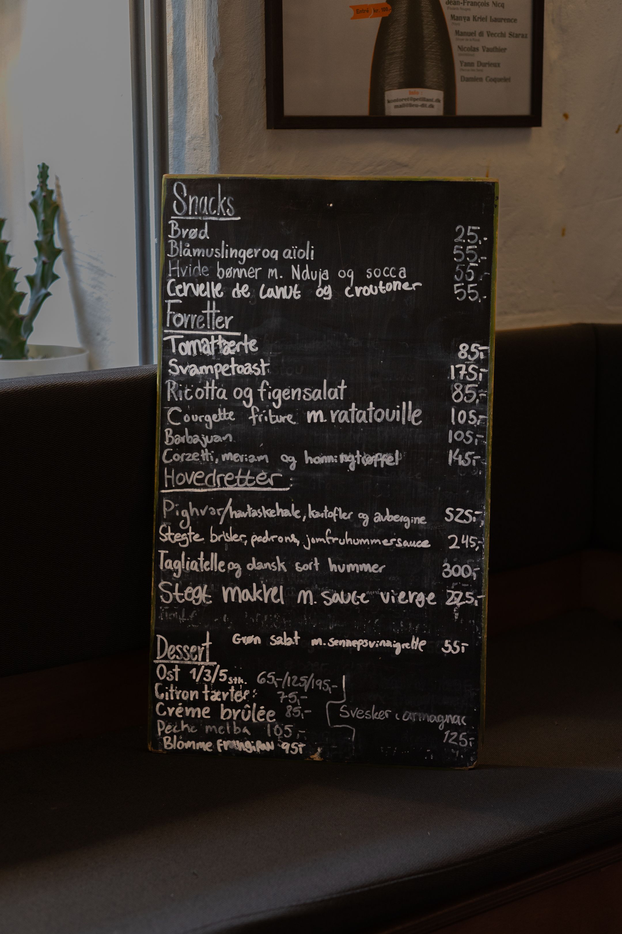 A chalkboard menu in French displaying various dishes and prices at a restaurant.