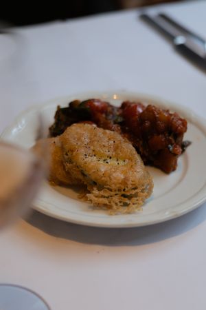 A plate featuring a golden brown biscuit and braised meat dish on a white tablecloth.