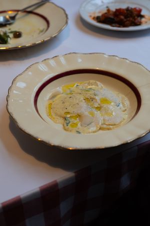 A cream-colored dish containing a delicate white sauce garnished with yellow ingredients.