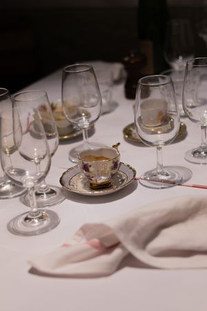 An elegant table setting with wine glasses and a decorative teacup on a white tablecloth.