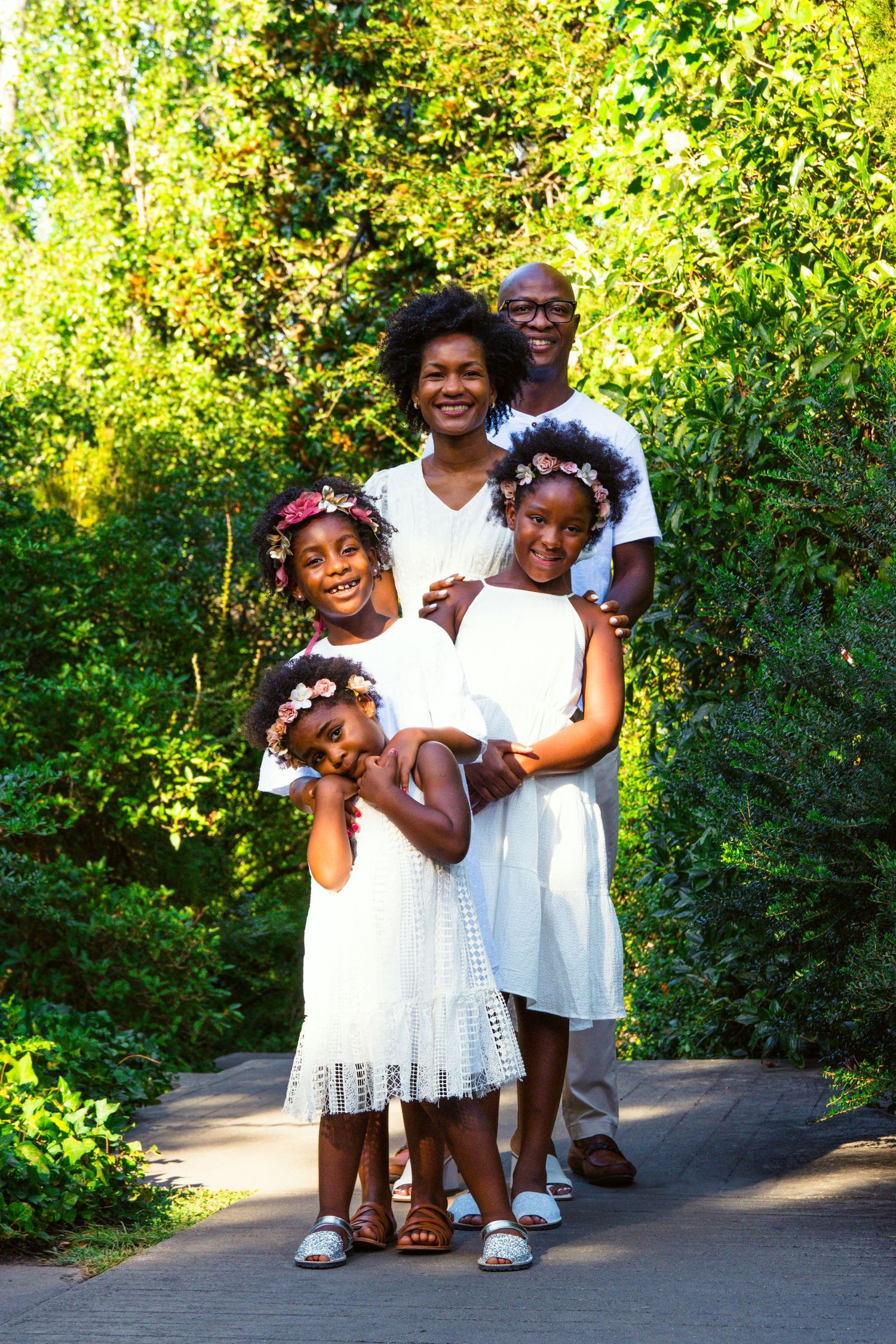 A joyful family portrait session with children wearing white dresses in a lush garden setting.