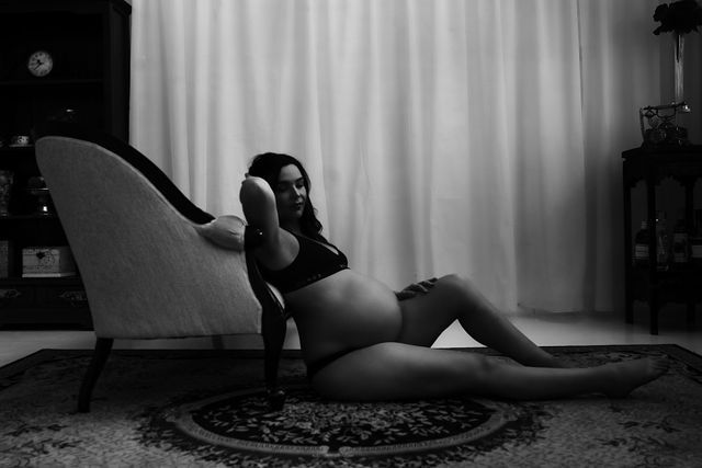 pregnant woman in underwear leaning on chase with legs stretched