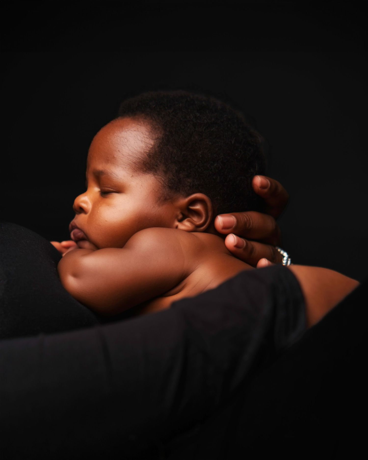Artistic black and white close-up series of sleeping baby on dark background.