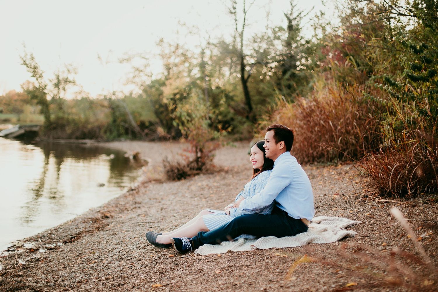 maternity woman sitting with man on blanket looking out at water