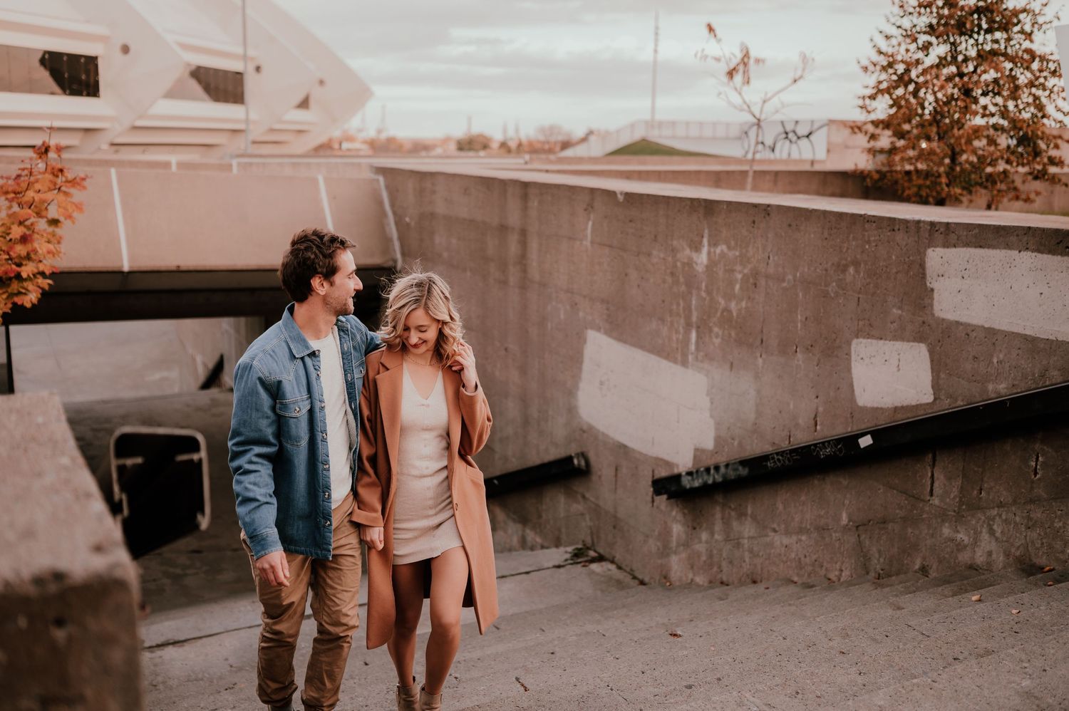 Couple walking together on rooftop during golden hour with urban backdrop.