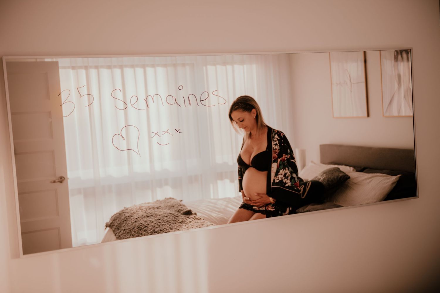 Woman in black lingerie poses on bed during intimate boudoir photoshoot.
