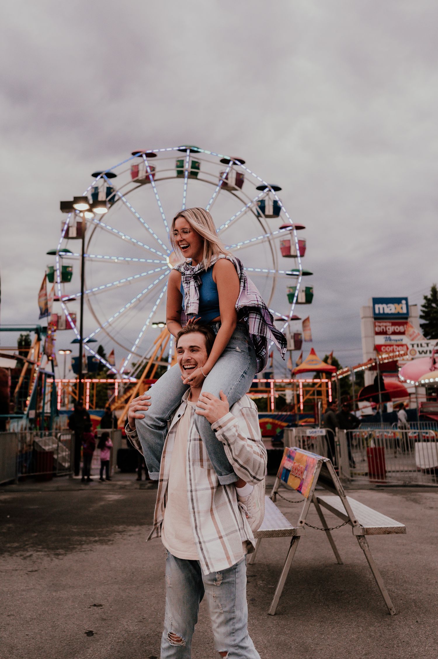 Couple having fun at carnival with ferris wheel in background.