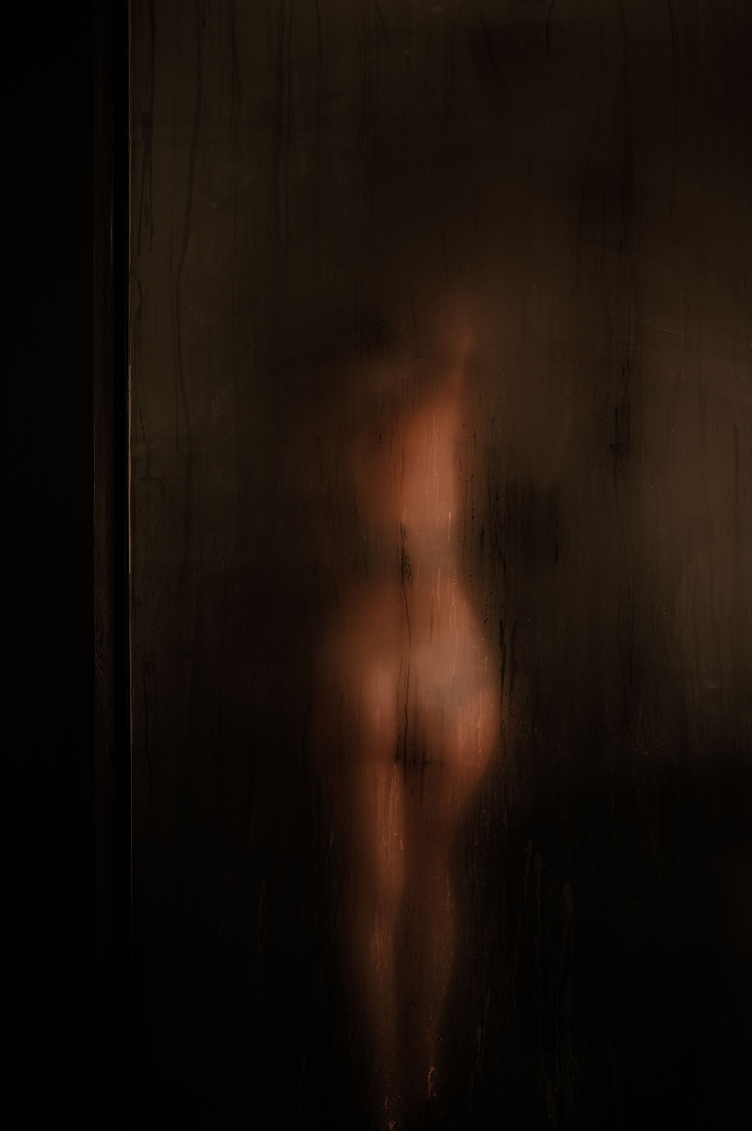 Artistic silhouette photo showing warm glowing light through frosted glass.