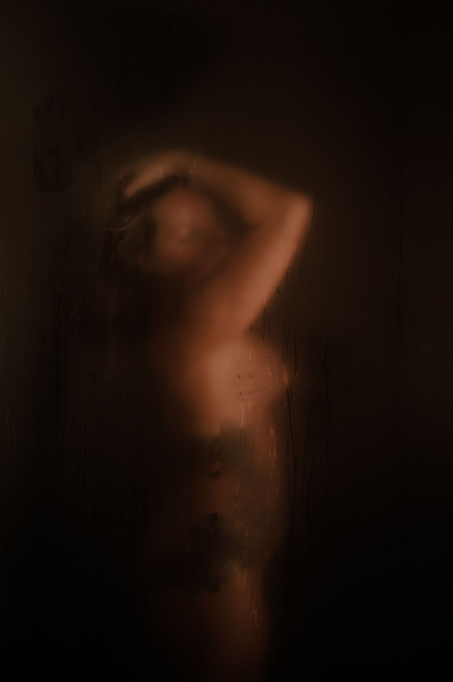 Artistic boudoir photograph with soft lighting and blurred shadows.