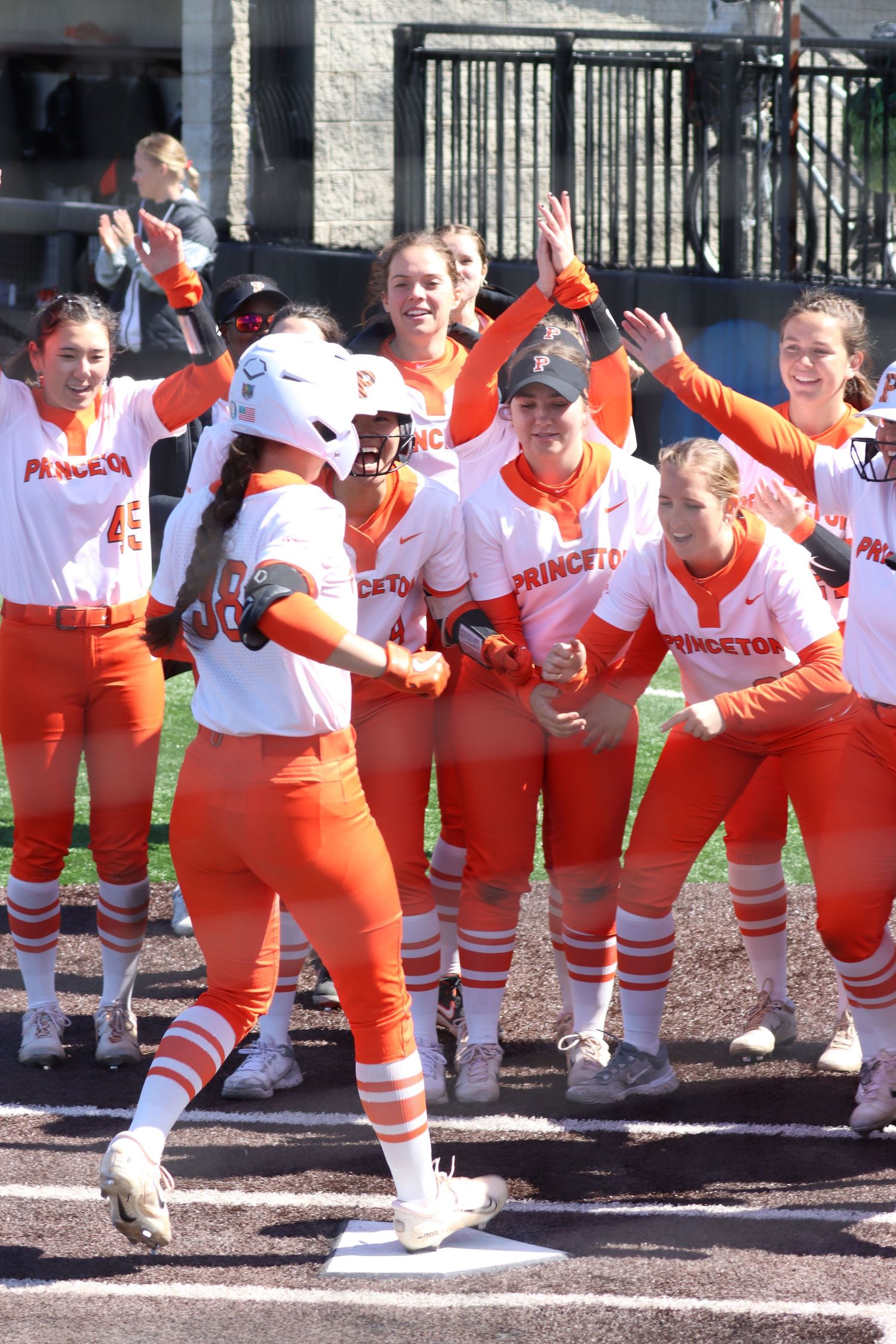 Princeton University softball players celebrate a grand slam home run while the player crosses the plate to win the game