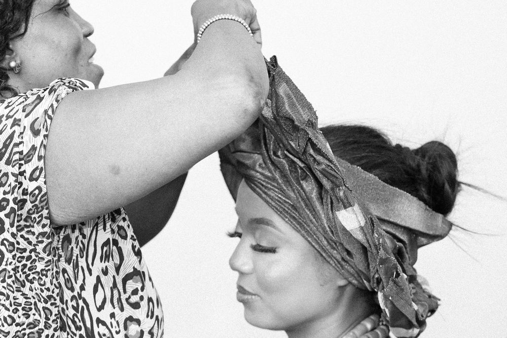 Black and white sequence showing hair styling and head wrap application.