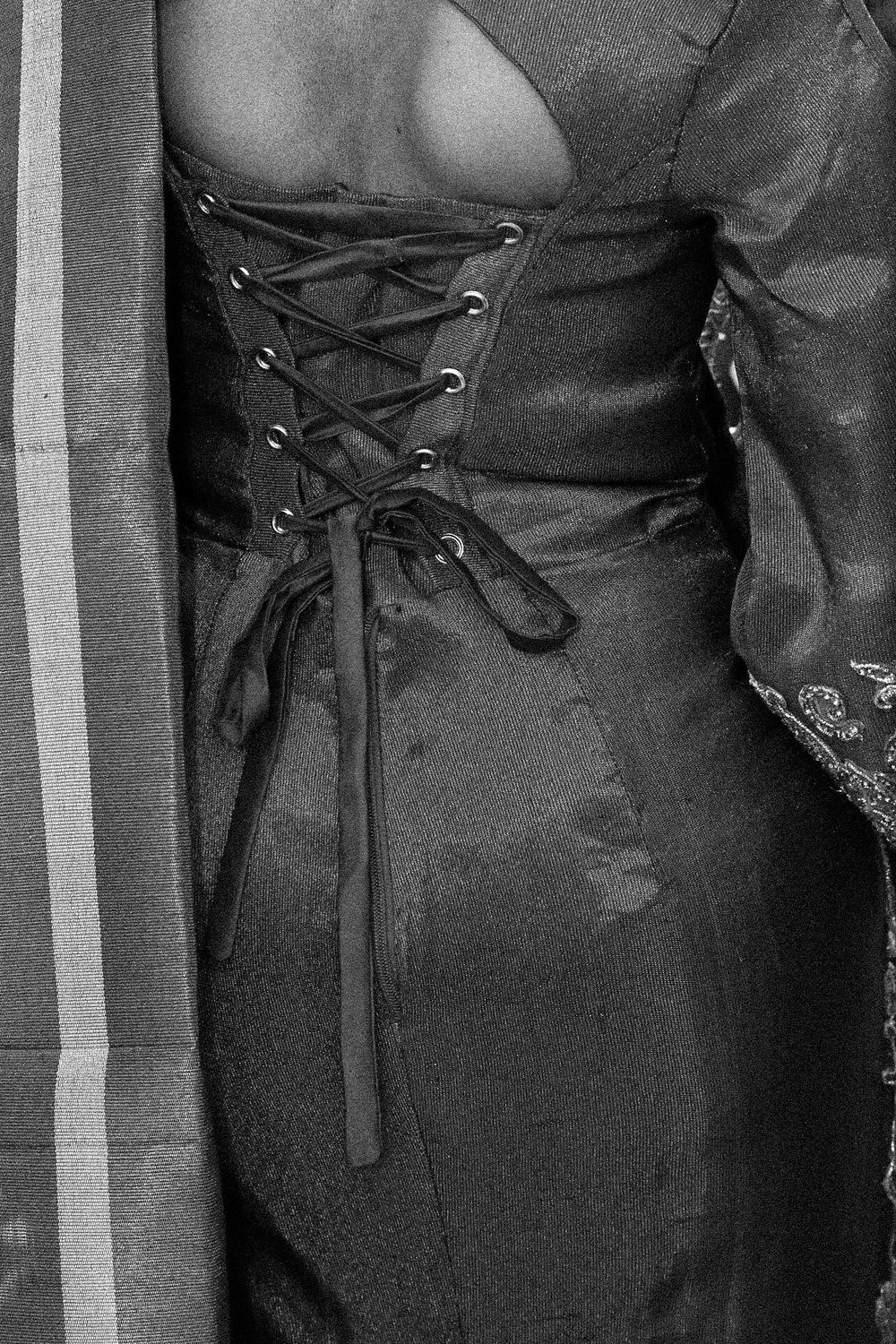 Close-up shots of black corset-style garment details showing lacing and fabric texture.