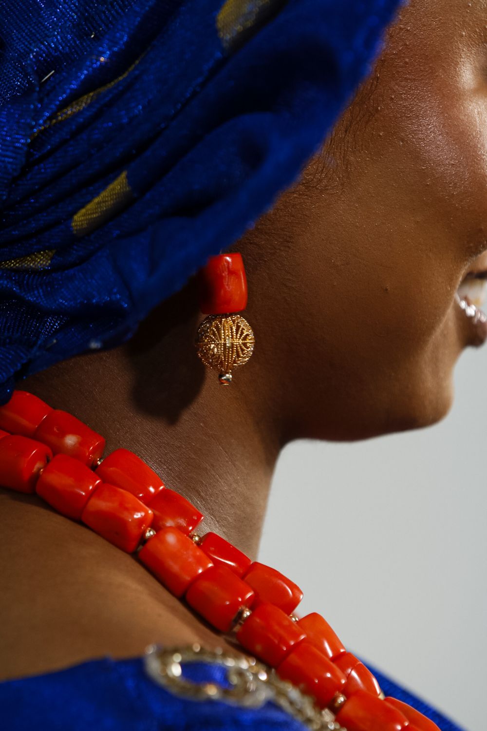 Detail shots of bright coral beaded necklace against blue fabric and skin.