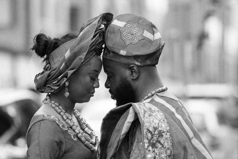 Black and white photos capture intimate moments between a couple in traditional African dress.