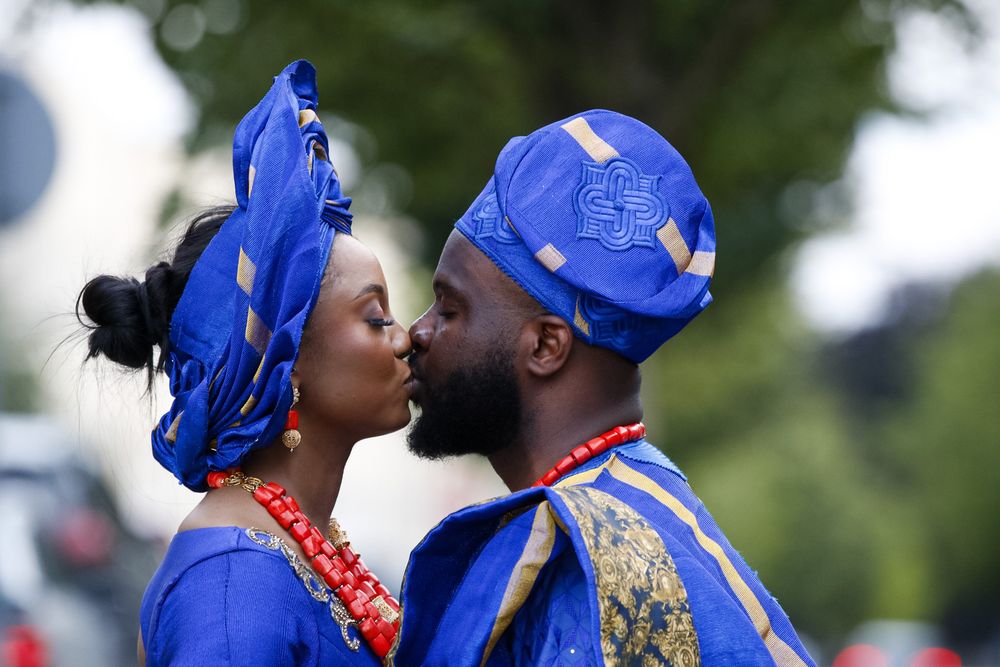 Couple in royal blue traditional Nigerian attire share romantic moments outdoors.