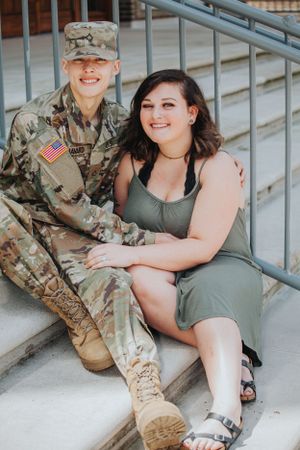 Military couple sharing tender moment while sitting on outdoor steps.