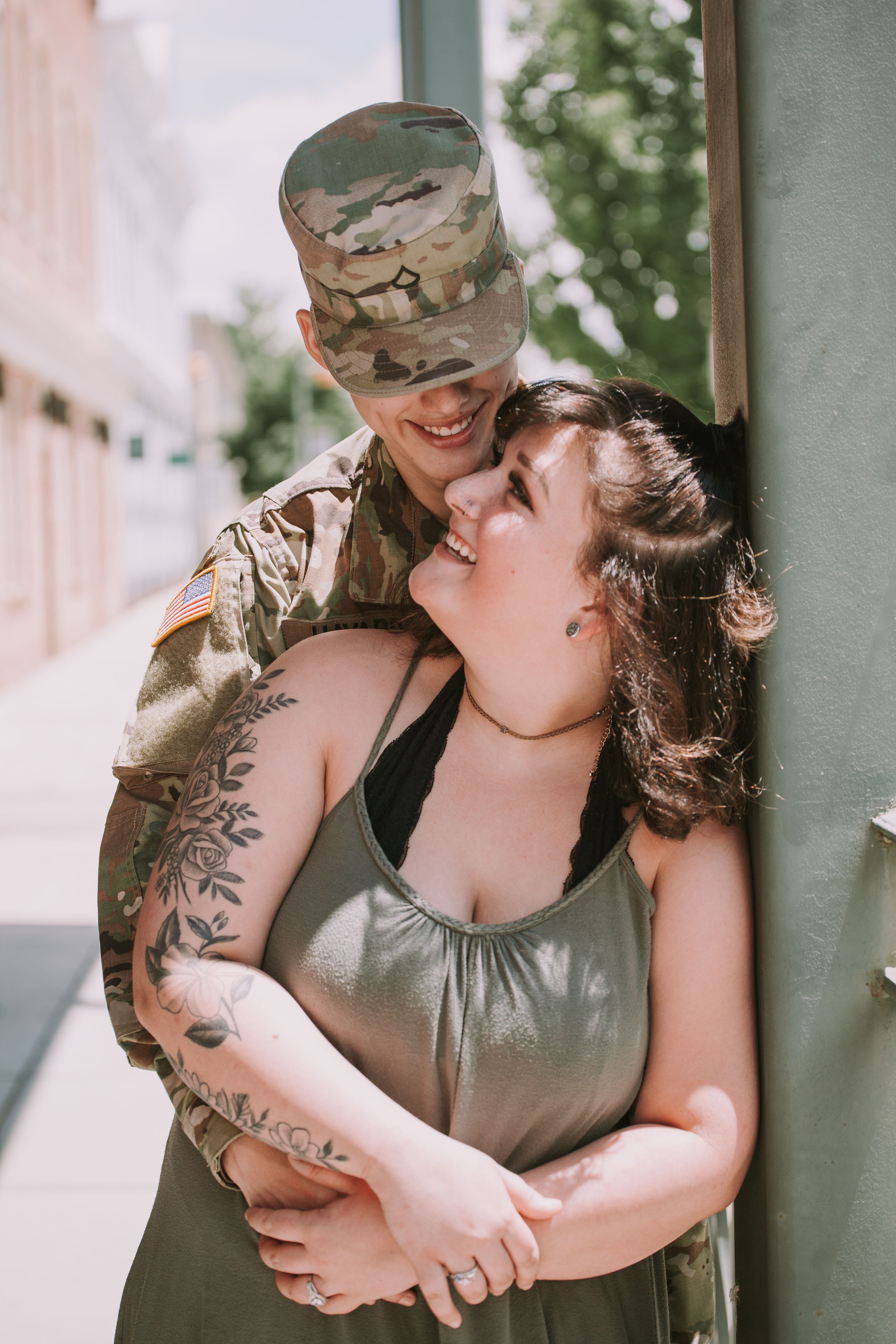 A couple embraces while laughing together on a covered porch.