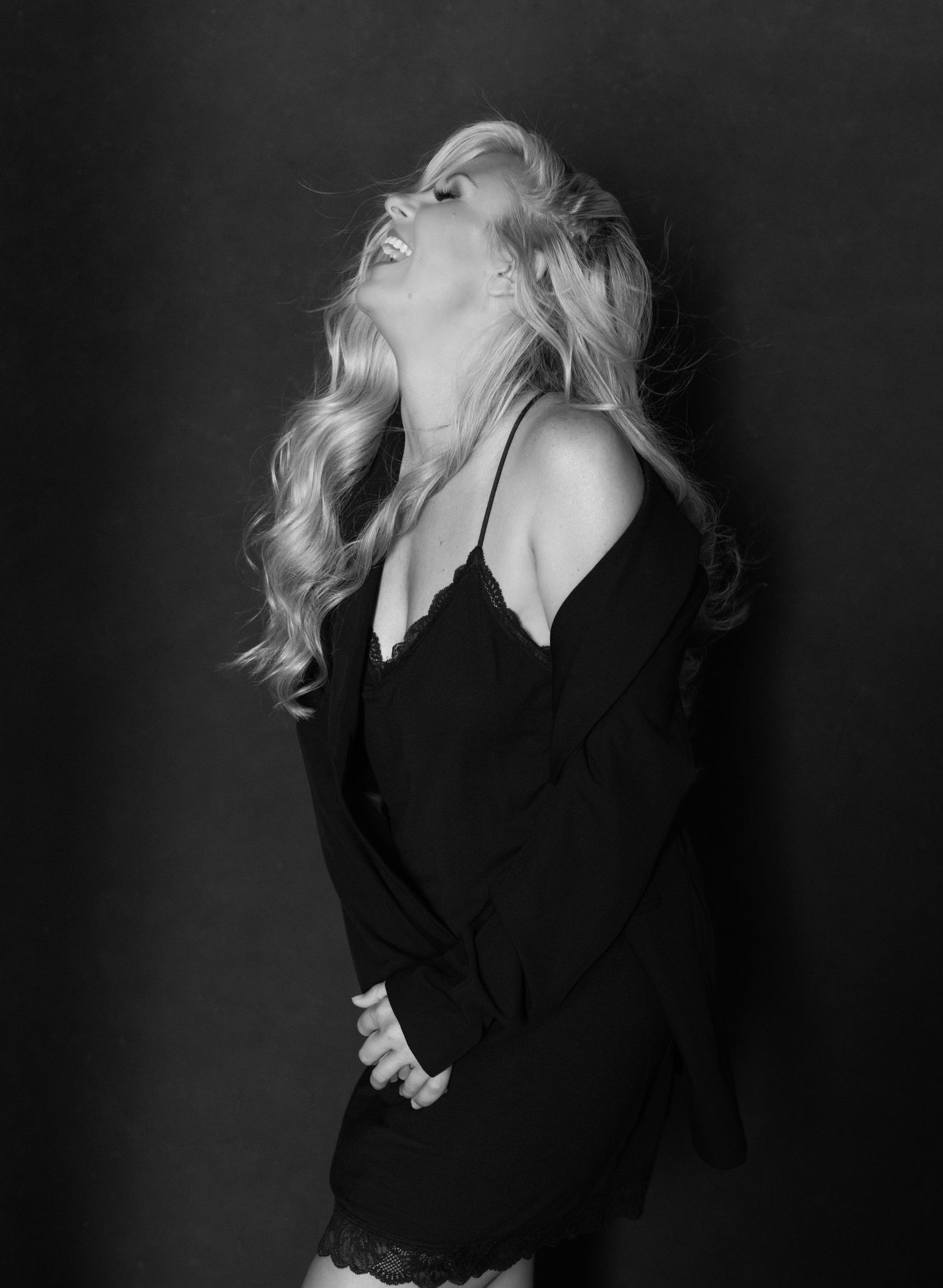 Dramatic black and white portrait of woman in black sweater against dark background.