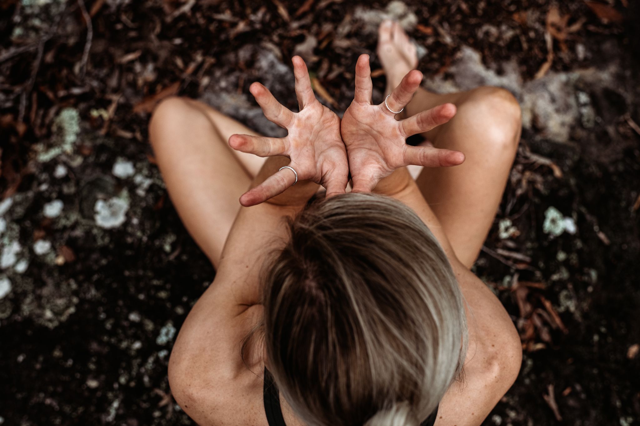 Overhead view of someone making a creative hand gesture against dark ground.