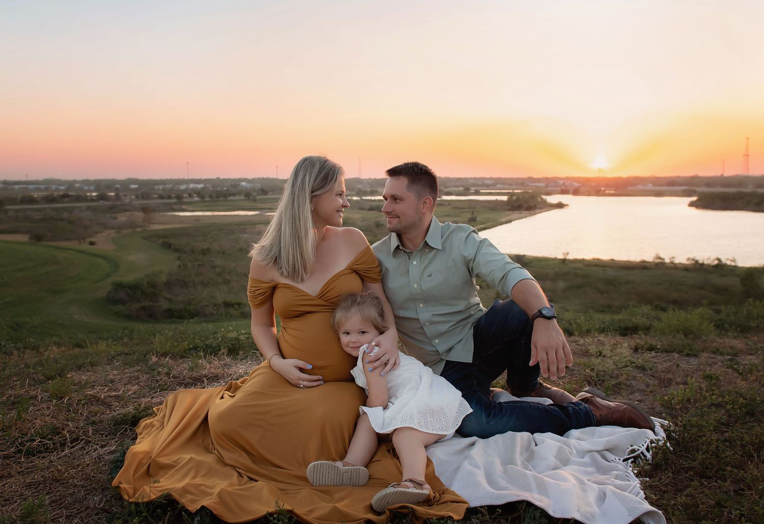Family in casual attire lounging on blanket during sunset photoshoot.