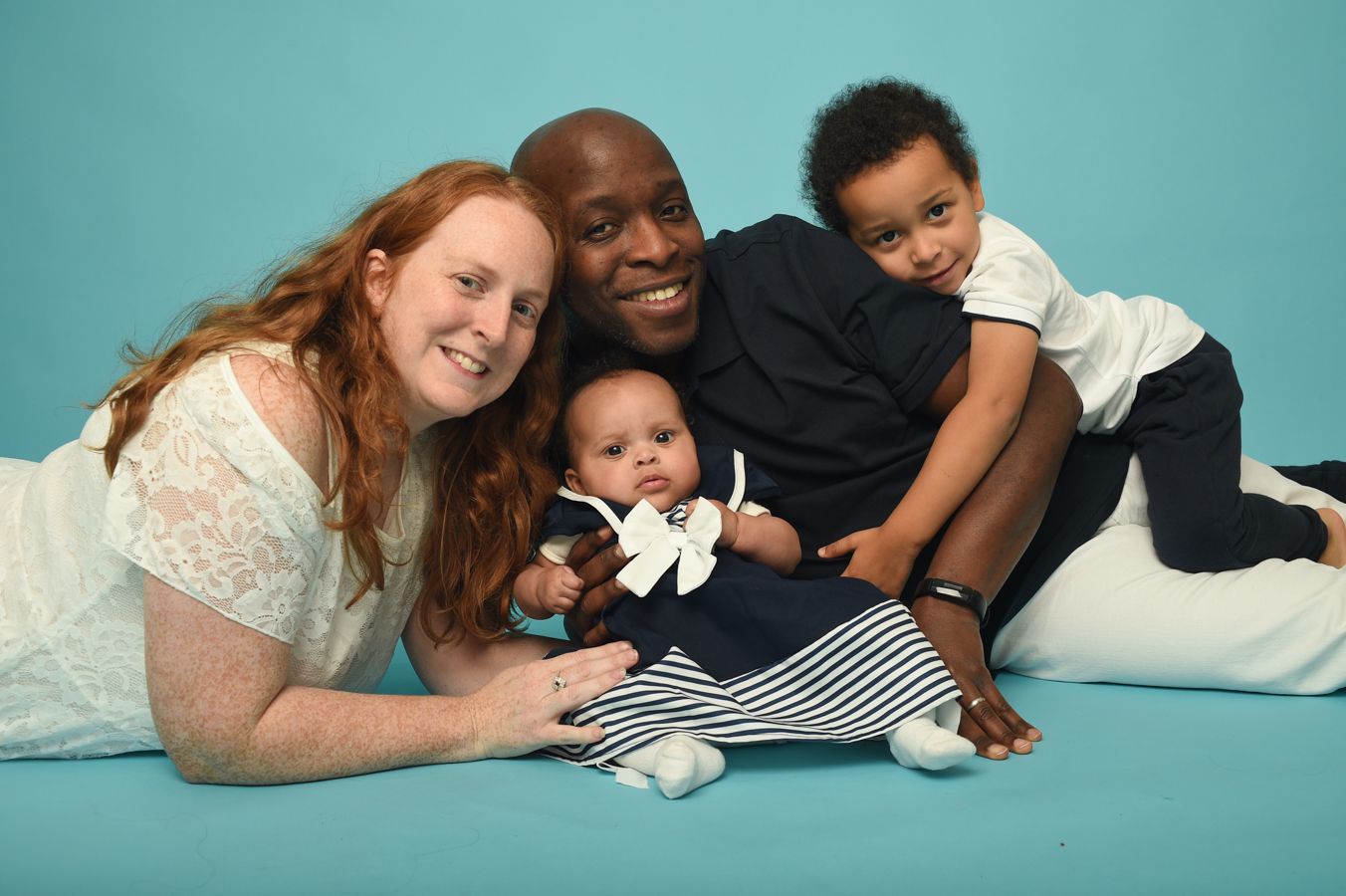 Family dressed in sailor suits pose on a Caribbean blue background, in my High Wycombe photo studio. Abigail's Studio