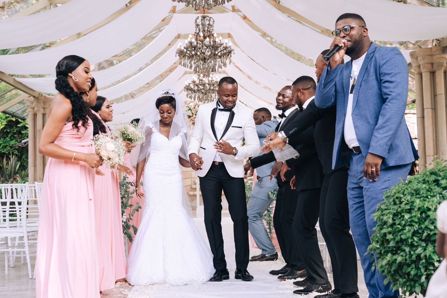 A bride and groom celebrate at their wedding ceremony surrounded by bridesmaids and groomsmen.