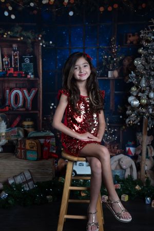 Holiday portrait with sparkly red dress in front of Christmas decorations.