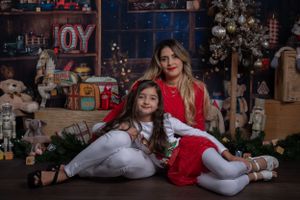 Festive holiday portrait with Christmas decorations and JOY sign in background.