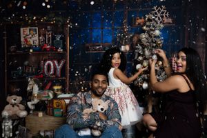 Family holiday portrait with Christmas tree and decorative props.