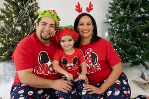 Family wearing matching Disney-themed Christmas pajamas and reindeer antlers.