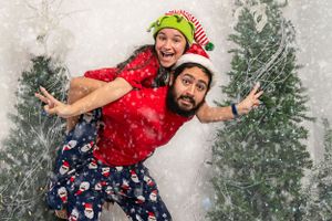 Playful holiday photo with matching Christmas pajamas against snowy backdrop.