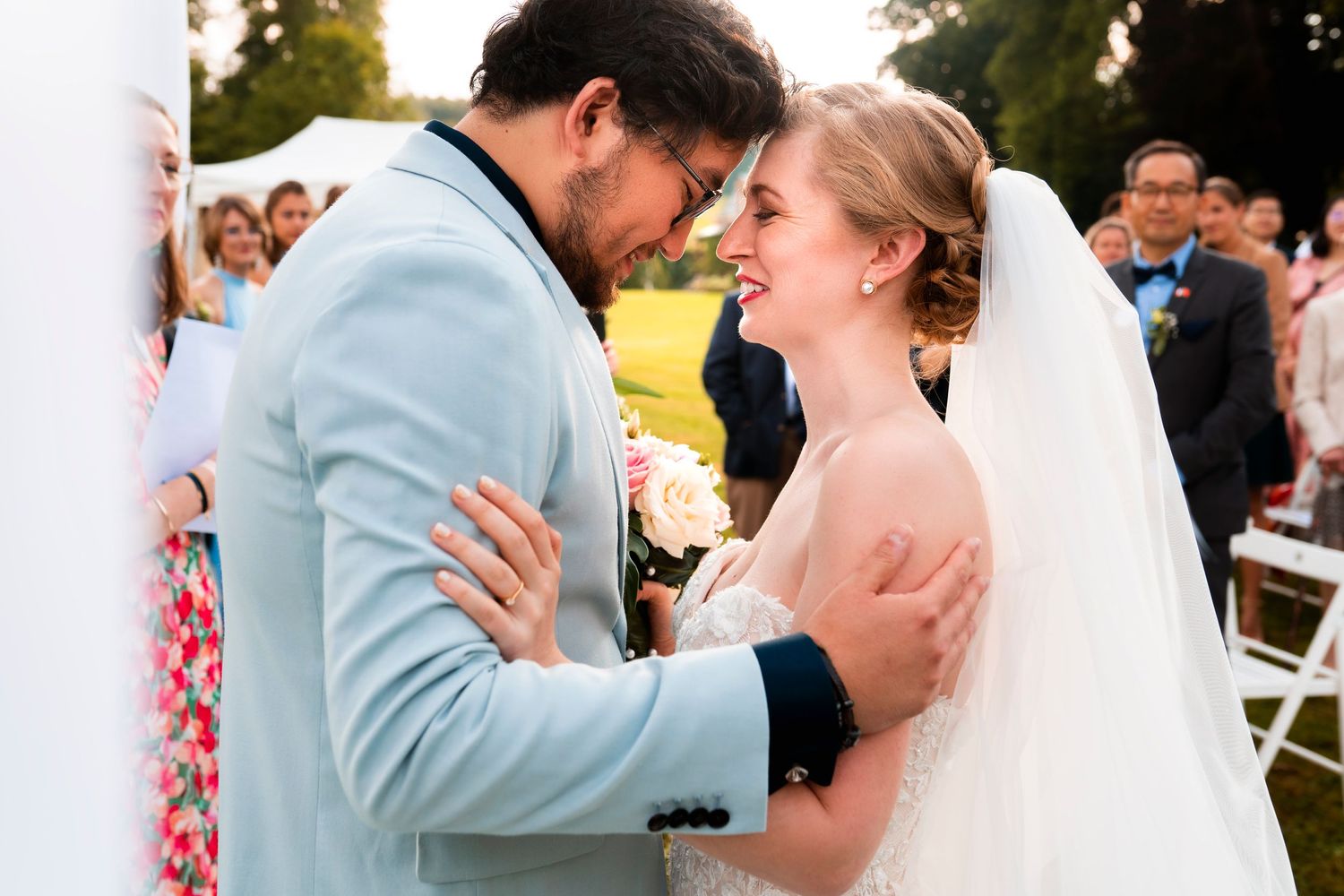 Tender moment between newlyweds during outdoor wedding ceremony.