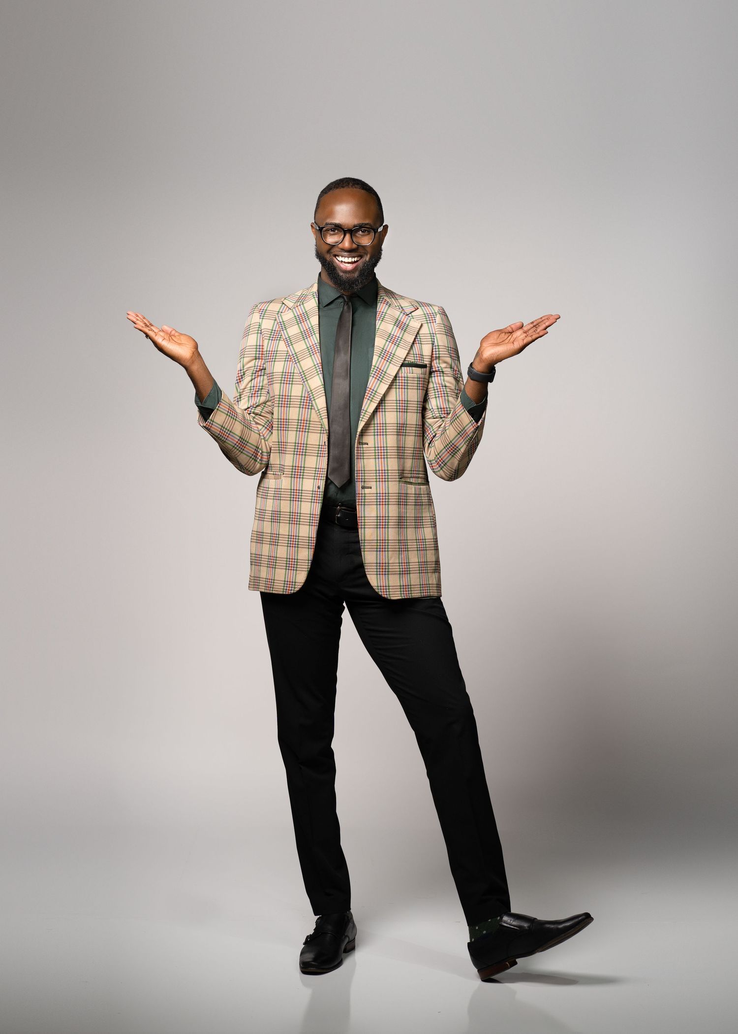 Stylish business attire featuring plaid blazer and green shirt with welcoming gesture.
