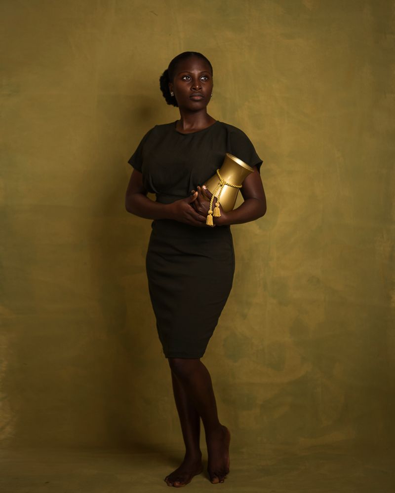 fine art photo of an african lady holding a golden jar/pot