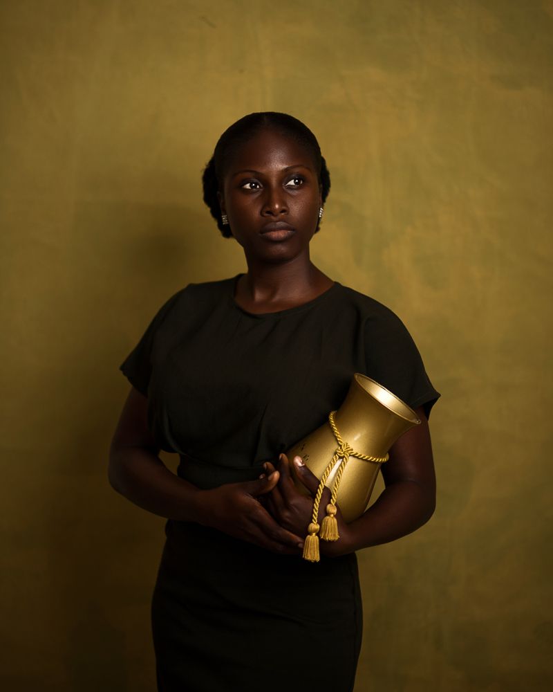 fine art photo of an african lady holding a golden jar/pot