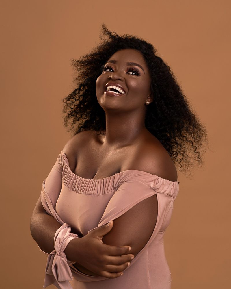 african plus size female portrait with curls and nude dress