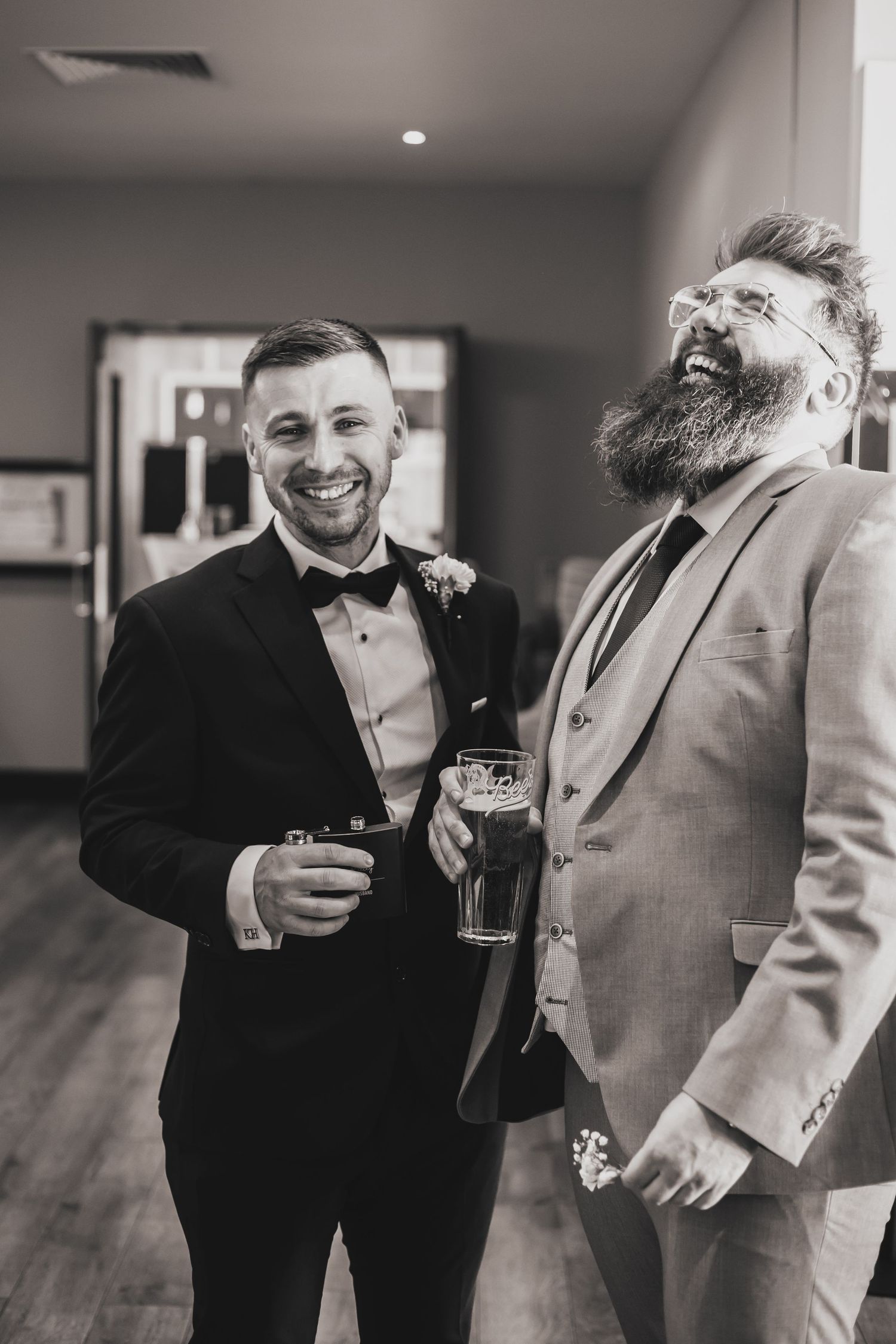two men laughing while at a wedding