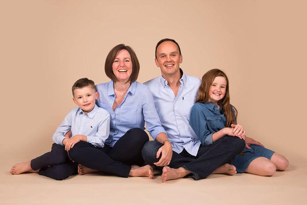 Studio family portrait with parents and children in coordinating blue outfits.