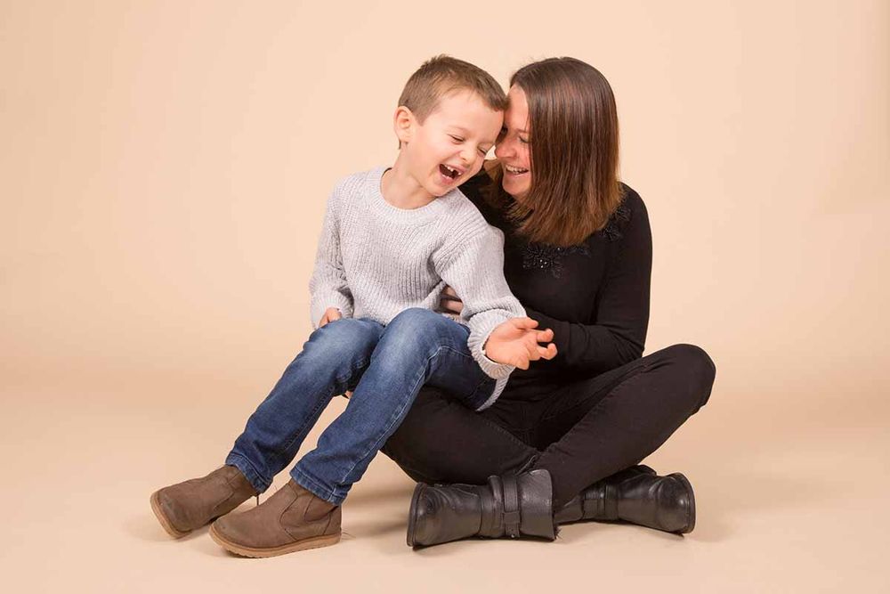 Candid moment between parent and child sitting on studio floor.