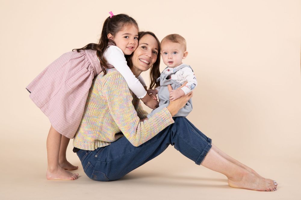 Candid studio portrait of three people sharing joyful moment on beige background.