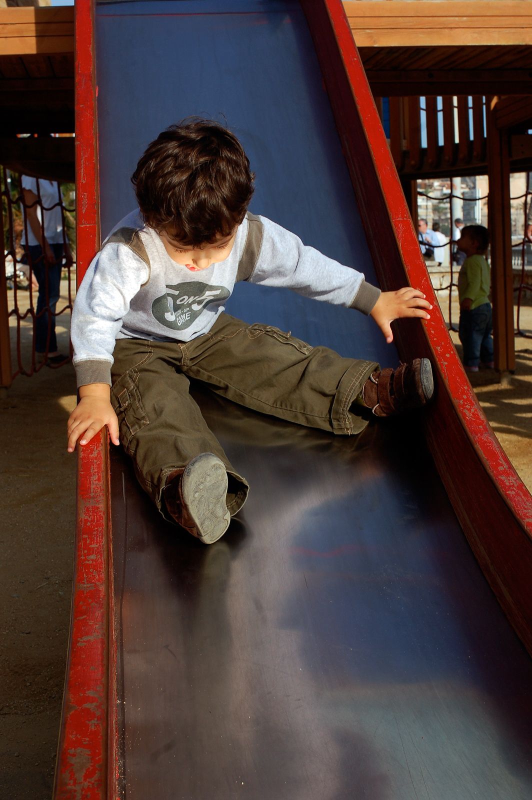 A portrait of a boy on a slide in a playground in Barcelona.