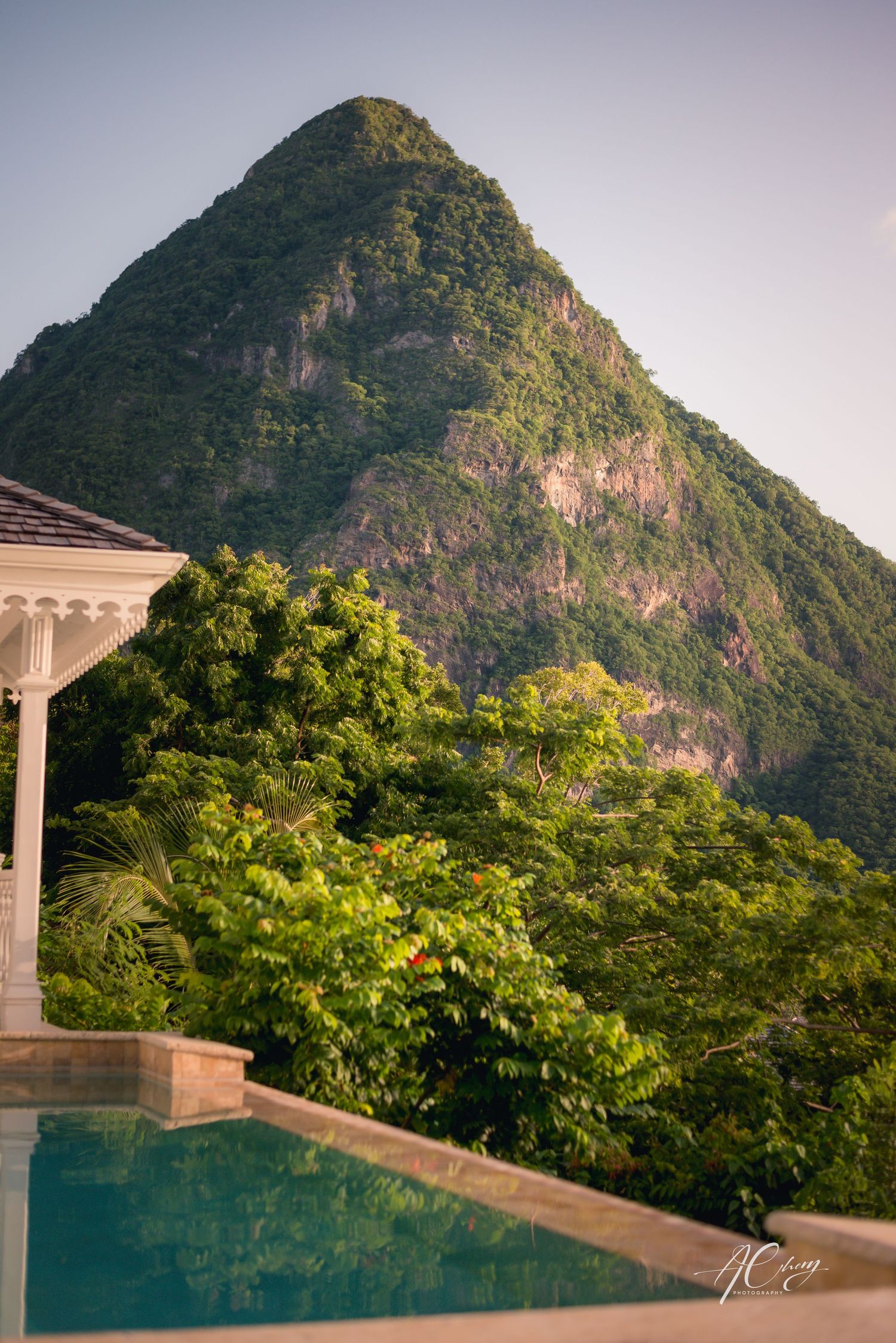 Luxury infinity pool overlooking a dramatic mountain peak surrounded by tropical vegetation.
