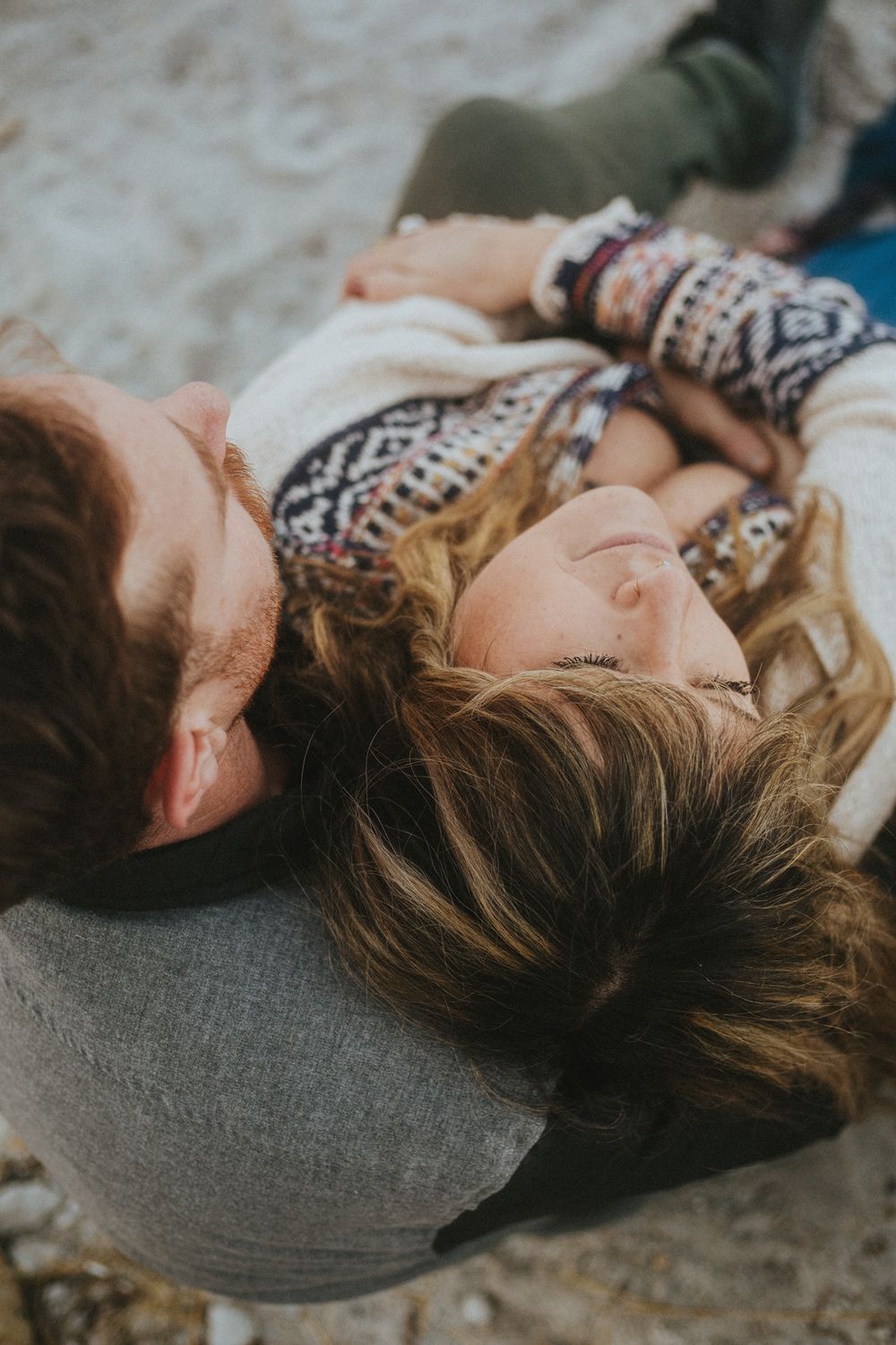 man and woman embrace sitting on beach, moody couples portrait